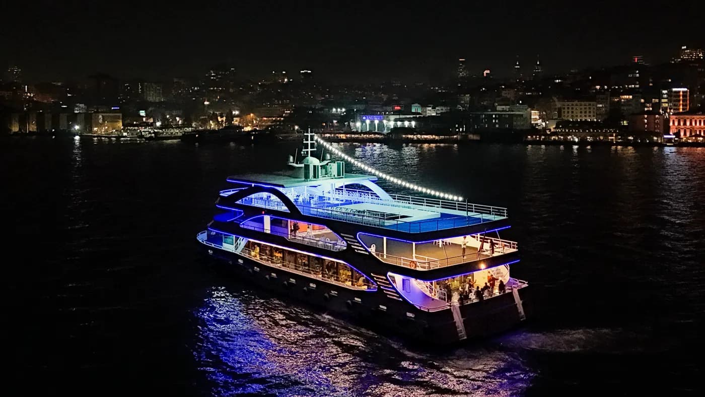 Touronic Cruise ship sailing the Bosphorus at night with Istanbul skyline behind it